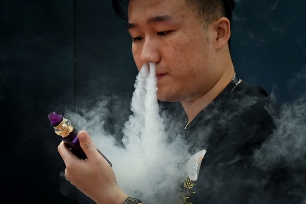 한 전자담배 업체 홍보 관계자가 지난 6월 베이징에서 열린 소비자가전 행사에서 전자담배를 피우고 있다. 사진=연합뉴스