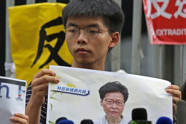 홍콩 민주화 시위 '우산혁명'의 주역 조슈아 웡이 18일 홍콩 정부청사 앞에서 홍콩 행정 수반인 캐리 람 행정장관의 사진을 든 채 그녀의 퇴진을 요구하고 있다. 사진=연합뉴스