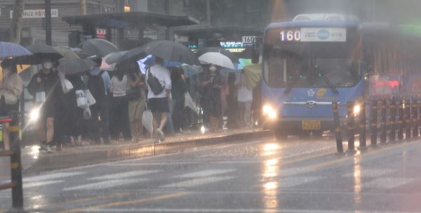 서울 시내 정류장에서 시민들이 비를 피하며 버스를 기다리고 있다. /연합뉴스