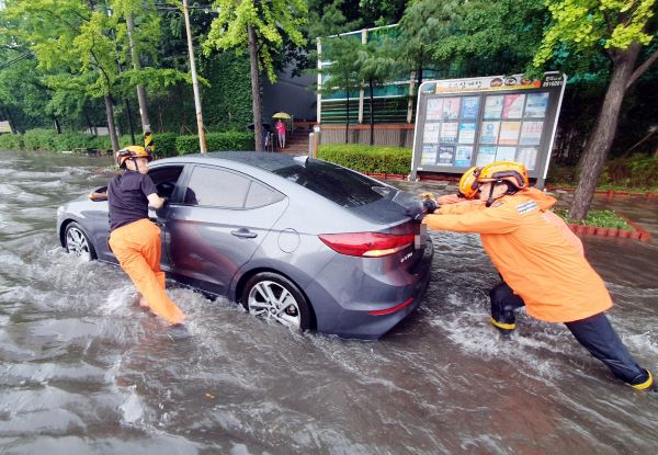 인천지역에 폭우가 내린 8일 인천시 미추홀구 용현동 한 도로에서 소방대원들이 침수된 차량을 안전한 곳으로 옮기고 있다. /연합뉴스