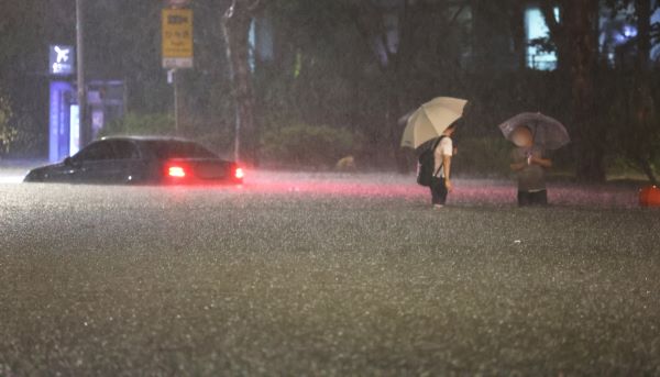 8일 밤 서울 강남구 대치역 인근 도로가 물에 잠기면서 차량과 보행자가 통행하는 데 불편을 겪고 있다.  /연합뉴스